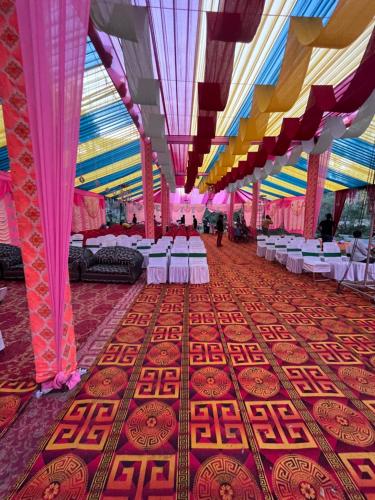 un gran salón de banquetes con mesas y sillas blancas en Rooms Chintpurni, en Bharwain