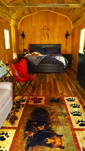 a bedroom with a bed and a red chair at Summer Trail Cabin 5 - Sleeps up to 4 in O'Brien