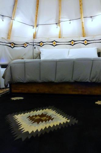 a bedroom with a white bed in a tent at Wild Horses Luxury Tipi - Adjustable King Bed in O'Brien