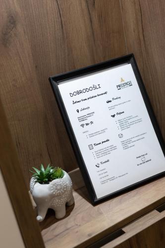 a menu sitting on a shelf with a potted plant at Spa Prestige Apartman Brcko in Brčko