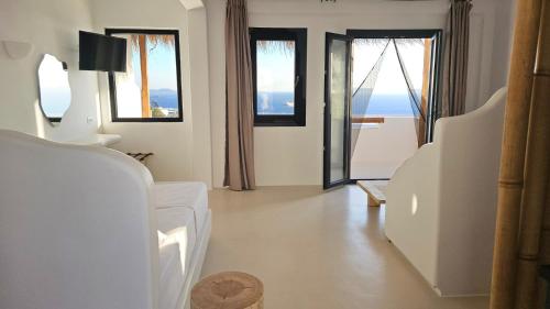 a living room with white furniture and large windows at ELLI TROPiCAL LUXURY SUITES SUNSET-INFINITY POOL- SEA SIDE-NEAR CENTER PARKING in Mikonos
