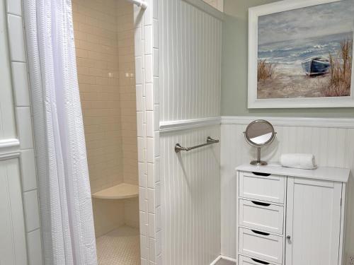 a white bathroom with a shower and a mirror at Hidden Treasure in Oak Island