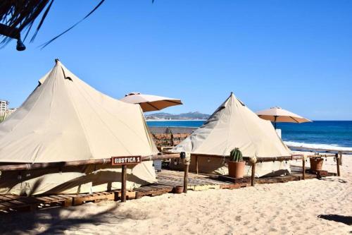 a group of umbrellas on a beach with the ocean at RUSTICO LOUNGE-Tipi With AC in front of the beach in San José del Cabo