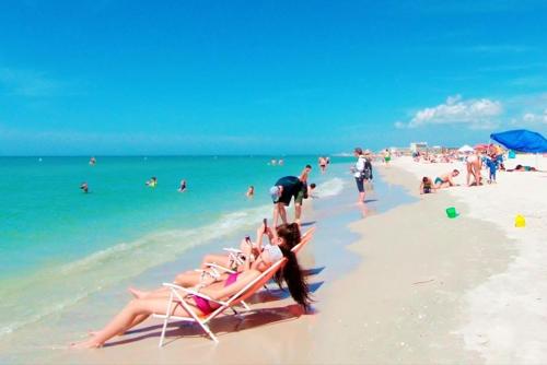 a group of people sitting in chairs on a beach at Boutique Beach Retreat in St Pete Beach