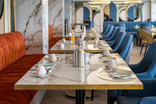a row of tables in a restaurant with blue chairs at Crowne Plaza Constanta - Mamaia Beach by IHG in Mamaia