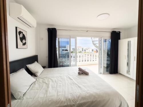 a bedroom with a large white bed and a balcony at Tranquil 2BR :Private Pool & Ocean Views in Callao Salvaje