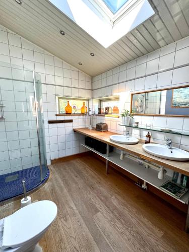 a bathroom with two sinks and a skylight at Unikt boende i egen del av hus nära stad och strand in Ystad