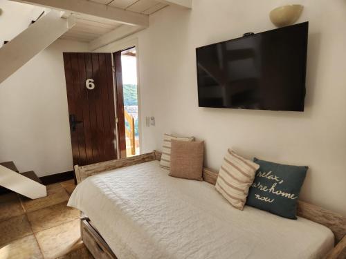 a bedroom with a bed with a television on the wall at Pousada Dreamland Buzios in Búzios