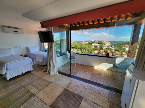a hotel room with two beds and a large window at Pousada Dreamland Buzios in Búzios