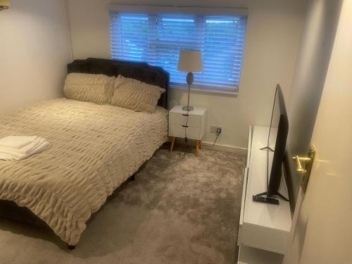 a bedroom with a bed and a television and a window at Room in Cheshunt in Cheshunt