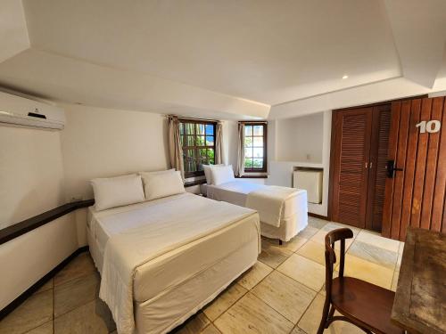 a bedroom with two beds and a desk and a table at Pousada Dreamland Buzios in Búzios