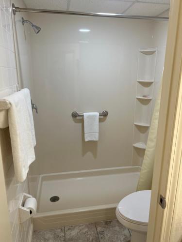 a bathroom with a shower with a toilet and towels at Town & Country Inn & Resort in Gorham