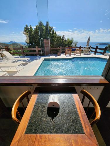 a swimming pool with a wooden table and a table at Pousada Dreamland Buzios in Búzios