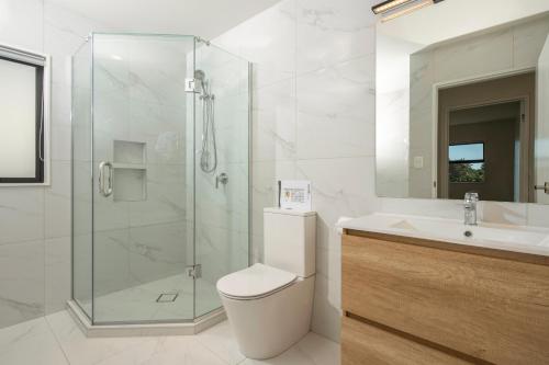 a bathroom with a shower and a toilet and a sink at modern immaculate residence in mount wellington in Auckland