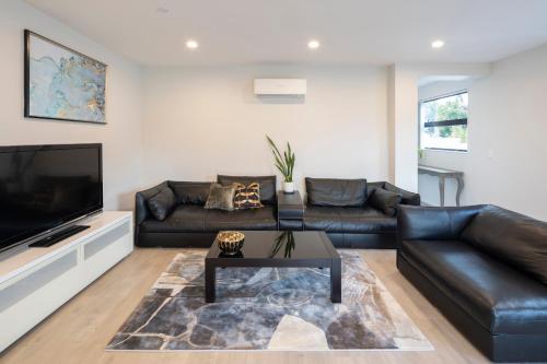a living room with leather furniture and a flat screen tv at modern immaculate residence in mount wellington in Auckland