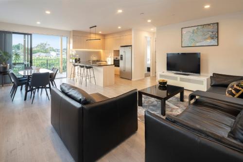 a living room with two couches and a dining room at modern immaculate residence in mount wellington in Auckland
