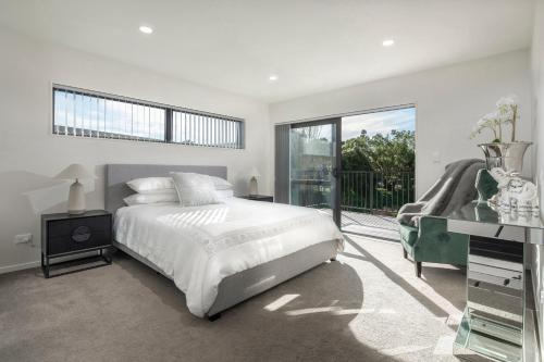 a white bedroom with a bed and a balcony at modern immaculate residence in mount wellington in Auckland