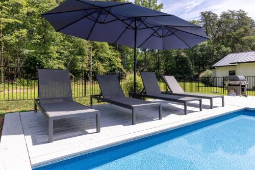 a group of chairs and an umbrella next to a pool at Oasis Near Charlottesville With Pool, Grill in Zion Crossroads