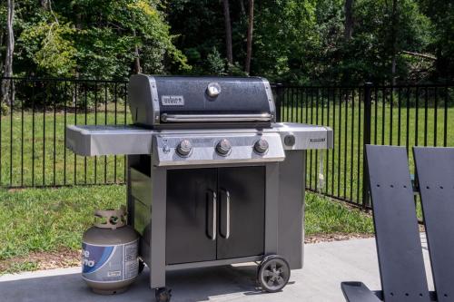 a barbecue grill sitting on a cart next to a fence at Oasis Near Charlottesville With Pool, Grill in Zion Crossroads