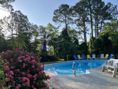 a swimming pool in a garden with chairs and flowers at Gulf Breeze Tranquil Retreat 10 min to Beach RV boat jet ski parking in Gulf Breeze