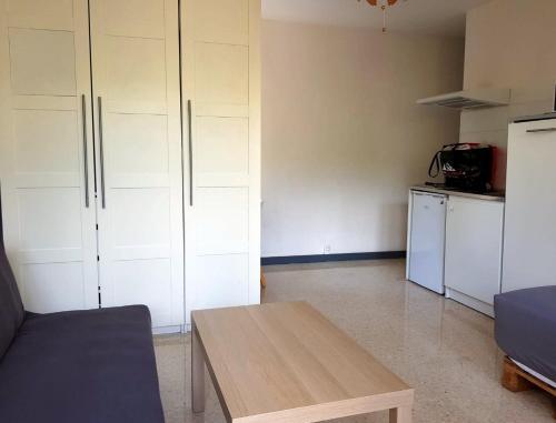 une chambre avec une table et une cuisine avec des placards blancs dans l'établissement Studio quartier hôpitaux facultés, à Montpellier