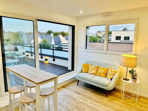 Cette chambre dispose d'un balcon avec une table et un canapé. dans l'établissement Le Refuge de lAlbatros Vert, à Donville-les-Bains