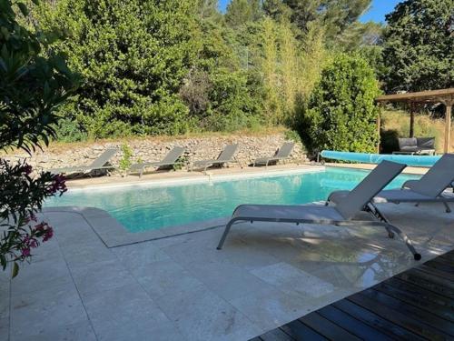 een zwembad met ligstoelen en een tafel bij Villa des 3 Ponts, Piscine au calme in Nîmes