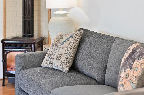 a gray couch with two pillows on it in a living room at Dos Hermanas Casita 4 Downtown Courtyard Patio in Santa Fe