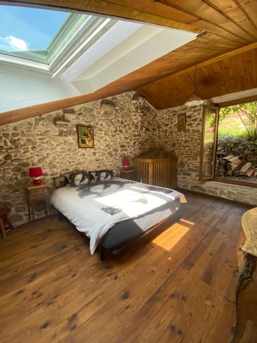 une chambre avec un grand lit dans un mur de pierre dans l'établissement Maison de montagne rustique, à Castanet-le-Haut