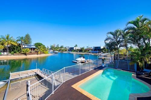 a swimming pool next to a river with a boat at Sandy Shores - Large Family Retreat in Gold Coast