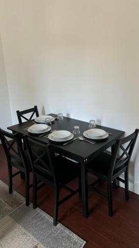 une table noire avec quatre chaises et des assiettes dans l'établissement Appartement style Haussmannien Dreux Centre, à Dreux
