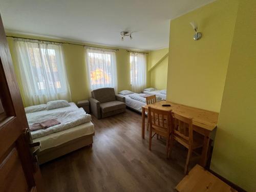 a room with two beds and a desk and a table at Pokoje REMUS in Szymbark