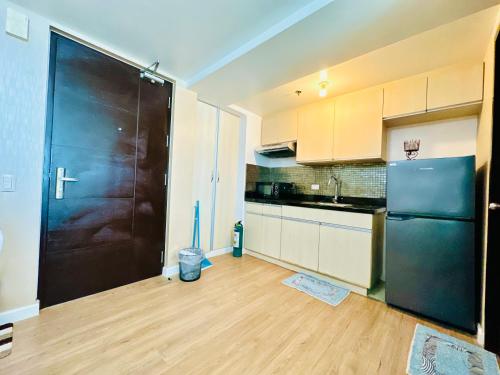 a kitchen with a black refrigerator and a wooden floor at Feels Like Home Condos Abreeza Place Tower 1 & 2 in Davao City