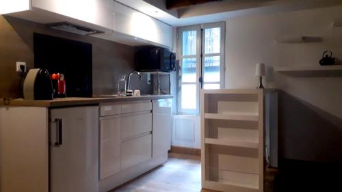une cuisine avec des placards blancs et une grande fenêtre dans l'établissement Studio place de la Comédie !, à Montpellier