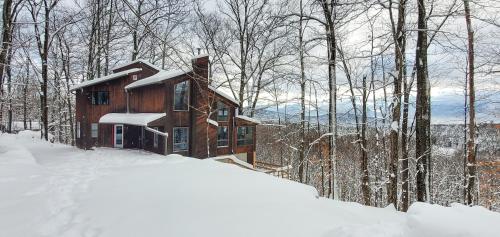 a log cabin in the woods in the snow at 5 Star Gorgeous Cliffside Chalet with Panoramic Views in Tannersville