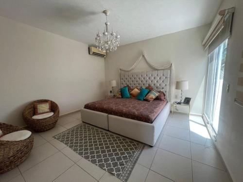 a bedroom with a large bed and a chandelier at La Villa de Sophie in Acapulco