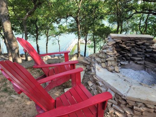 two red chairs sitting next to a stone fireplace at Lakefront, Private Dock, Spectacular Views in Bridgeport