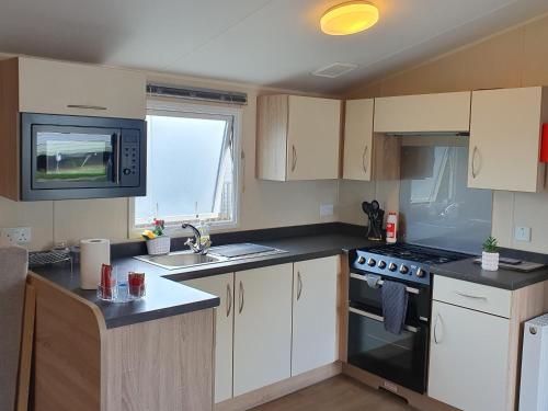 a kitchen with white cabinets and a stove top oven at Billing Aquadrome - Alberta Caravan 2 Bedroom Sleep 6 in Northampton