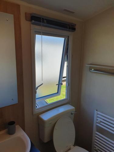 a bathroom with a toilet and a window at Billing Aquadrome - Alberta Caravan 2 Bedroom Sleep 6 in Northampton