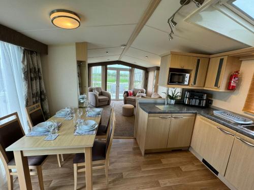 a kitchen and living room with a table and chairs at Golden Anchor - The Chamonix - Coastal Caravan Breaks in Chapel Saint Leonards