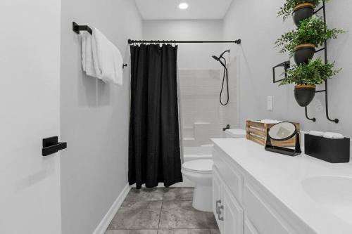 a bathroom with a toilet and a black shower curtain at Paradise Coachella NEW Salt Water Pool & Landcape in Coachella