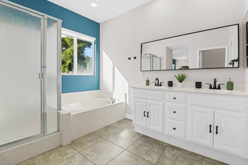 a bathroom with a tub and a sink and a mirror at Paradise Coachella NEW Salt Water Pool & Landcape in Coachella