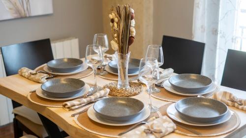 a wooden table with plates and wine glasses on it at H&H Suite Abrazo de Granada in Granada