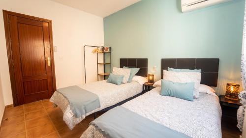 two beds in a room with blue and white at H&H Suite Abrazo de Granada in Granada