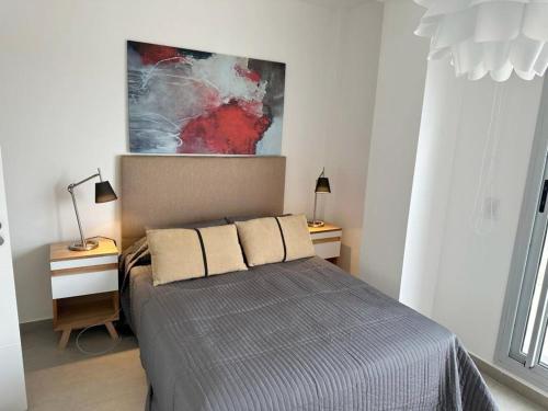 une chambre avec un lit avec deux lampes et un tableau dans l'établissement Lujoso Penthouse a estrenar en Sofisticado Barrio y Edificio Vista panorámica 100m2 Gimnasio Piscina Lujoso Salon de Fiestas Parking privado con acceso directo al departamento, à Buenos Aires