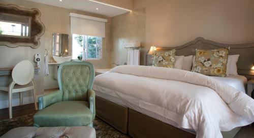 a bedroom with a large bed and a green chair at Hermanus Boutique Guest House in Hermanus