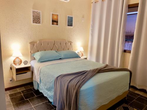 Un dormitorio con una cama con almohadas azules y una ventana. en Casa Barracuda, en Búzios