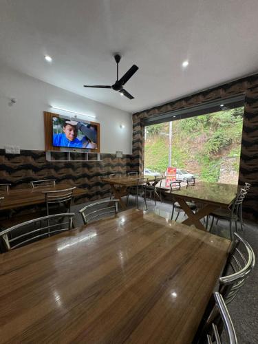 BarkotHotel Rest and Bite的用餐室配有大木桌和平面电视。