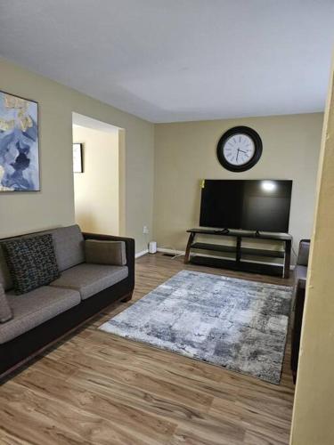 a living room with a couch and a clock on the wall at Michele Palace in Hyattsville