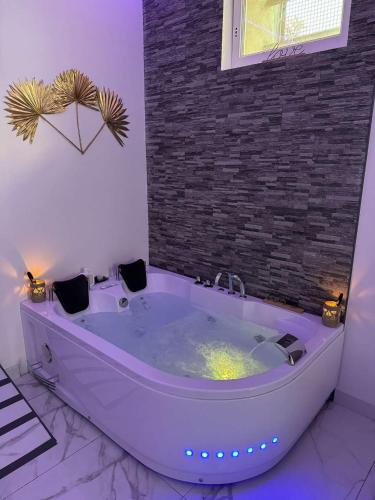 a large white tub in a room with a brick wall at Suite GOLD by L Amaryllis I Jacuzzi & Sauna privé I Centre Béziers Arrivée autonome in Béziers